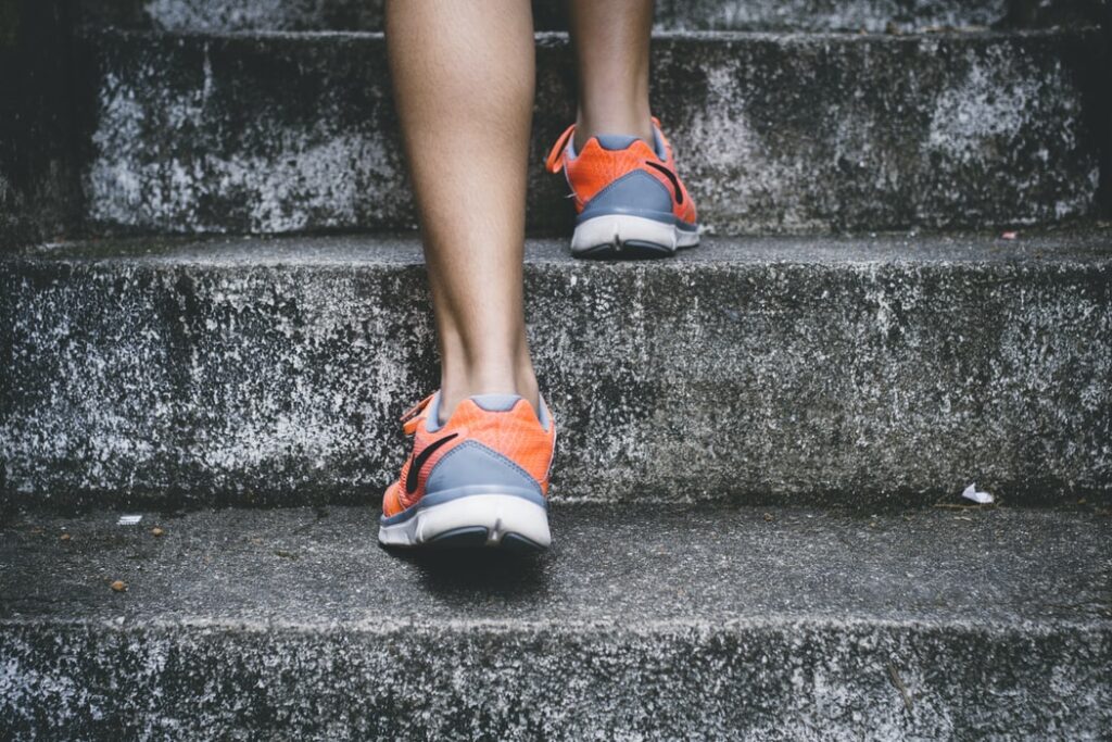 A person in running shoes climbing a flight of concrete steps
