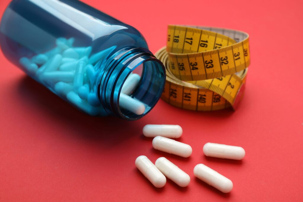 Prescription weight loss medication in a jar beside a measuring tape
